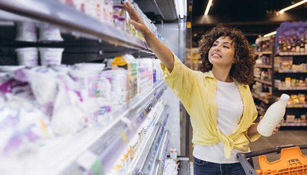 Woman shopping in dairy aisle in grocery store.
