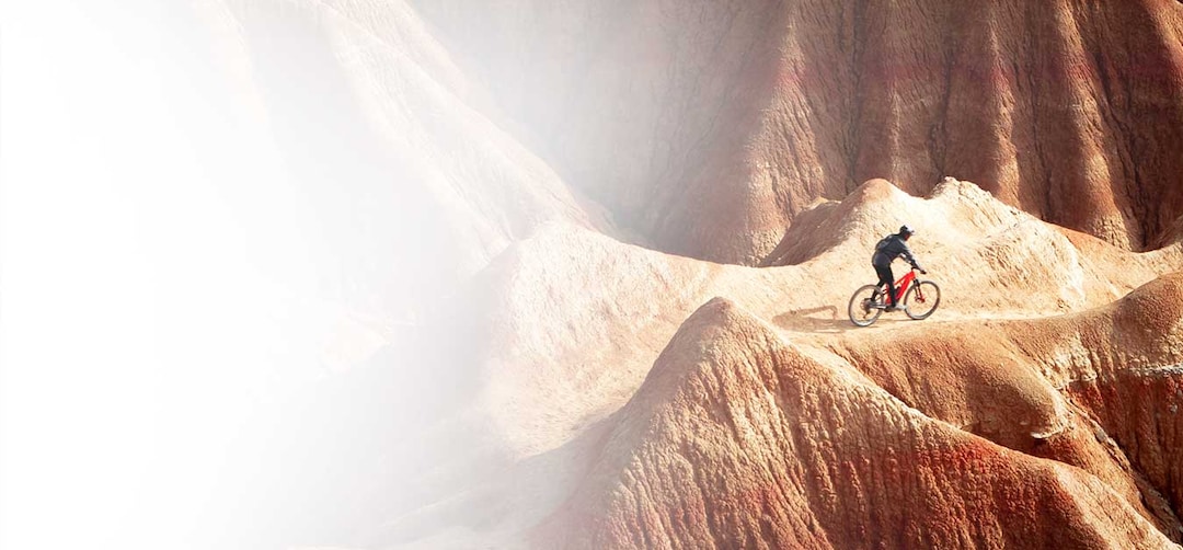 An image of a cyclist riding a bike on rocky red terrain