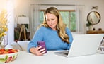 Woman with laptop holding phone