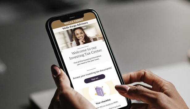 Hands holding a mobile phone displaying the Wells Fargo Advisors Tax Center page in the Wells Fargo Mobile® app.