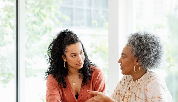 A younger woman and an older woman looking at each other and conversing.