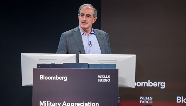Wells Fargo and Bloomberg logos behind panelists with Military Appreciation signage in front of speaker