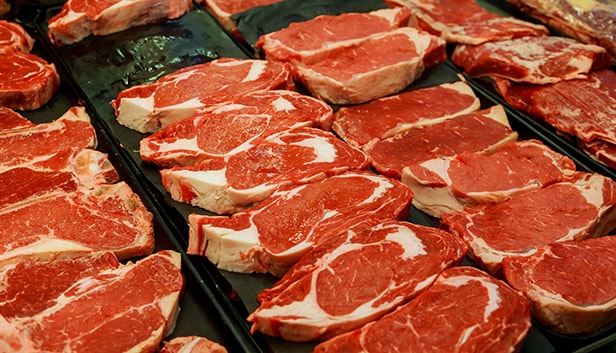 Raw beef steaks arranged on a tray, ready for purchase.
